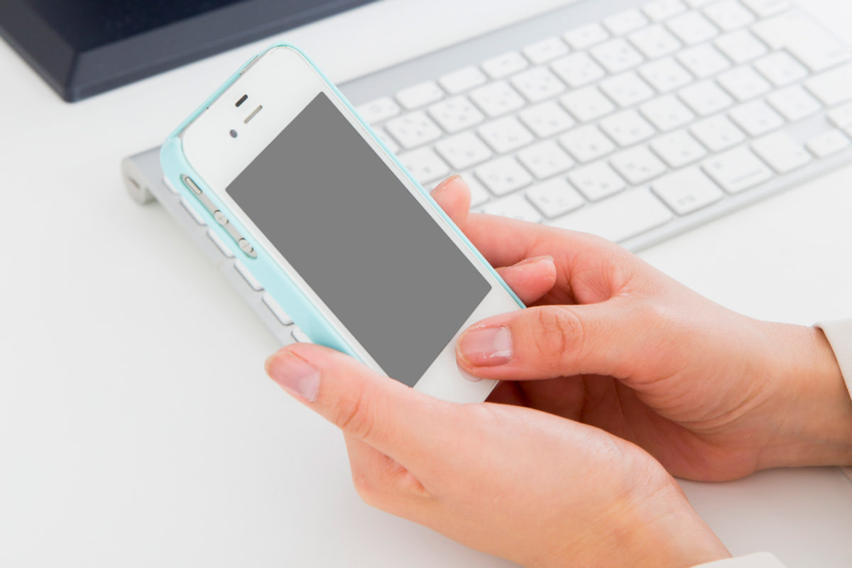 iPhoneのホームボタンを押しているイメージ写真