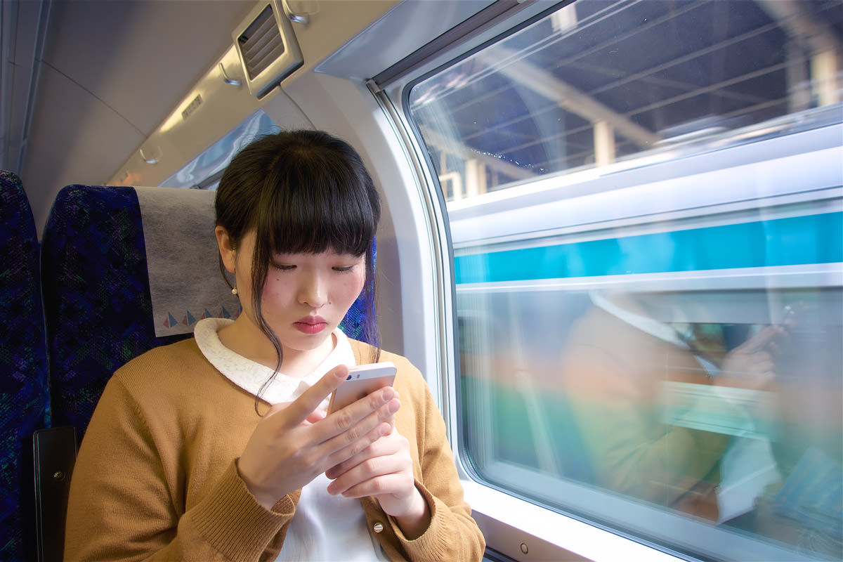 電車の中でiPhoneの設定を見直すイメージ写真