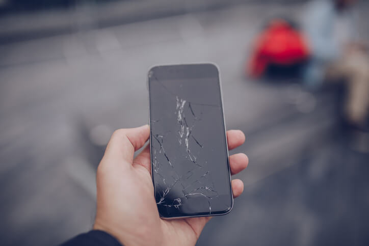 手で画面の割れたスマホを持っている