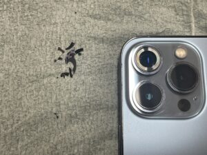 カメラ周りの割れたガラスを丁寧に除去し新しいレンズを取り付けているiPhone13Pro