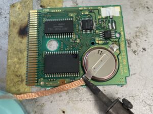 GBCソフトの基板へのはんだ付け作業。古い電池を取り外し、新しいタブ付き電池を実装中。 (Soldering a new battery onto a Game Boy Color cartridge PCB)