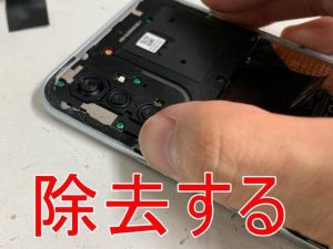 背面パネルを本体フレームを接着した粘着テープを除去しているRedmi Note 10 JE