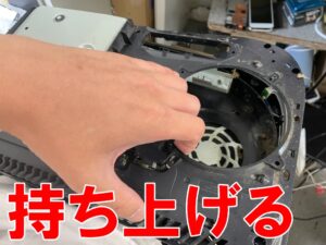 内部プラスチックフレームを持ち上げようとしている内部クリーニング中のPS5